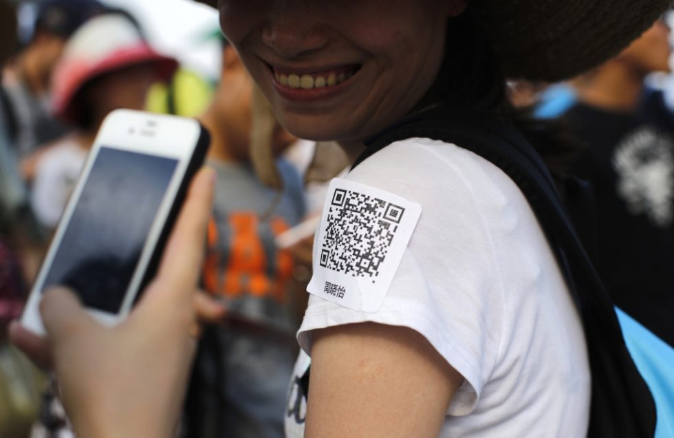 A man uses his phone to scan a QR code sticker, which is used to share personal information, during a matchmaking event in Jinshan beach